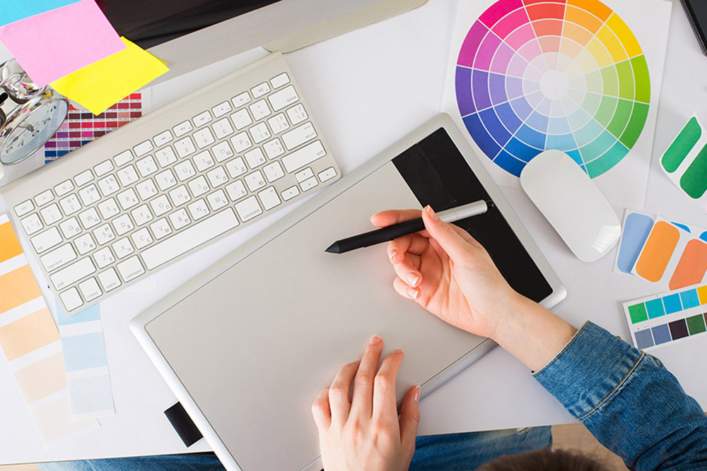 Young pretty Graphic designer using graphics tablet to do her work at desk